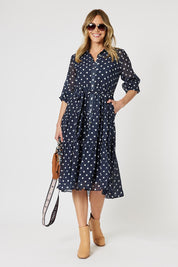 A model wearing the Sorrento Dress in colour Navy (Blue), from the front, showing the whole outfit