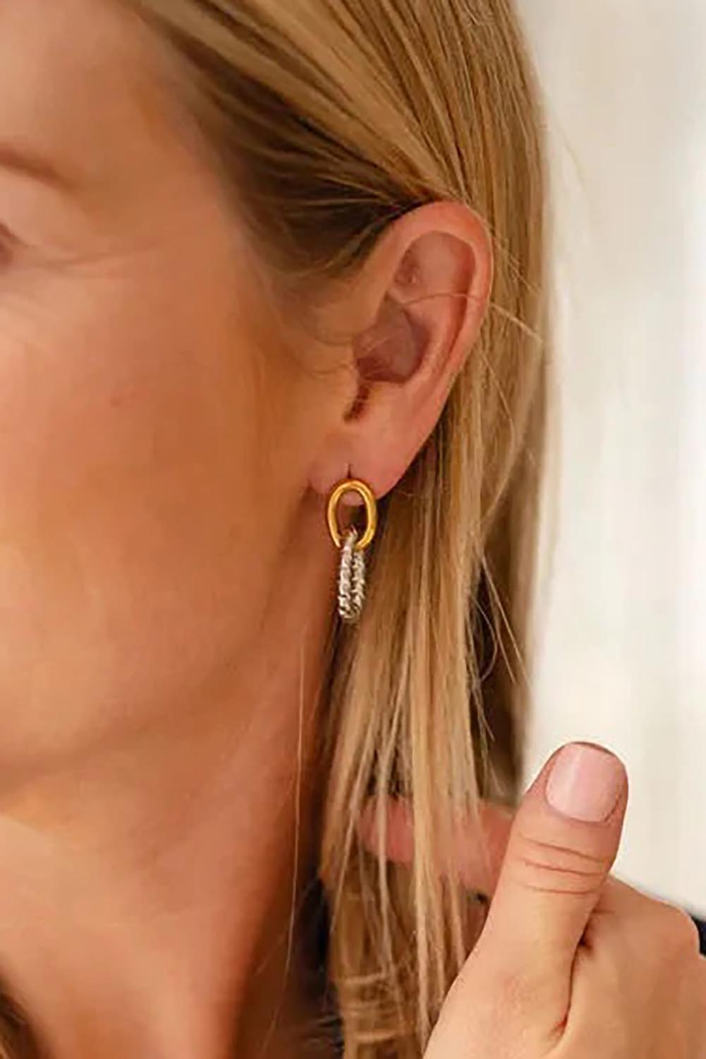 A model wearing the Didi Drop Dual Metallic Earring in colour Goldsilver (Metallics), from the front, cropped image