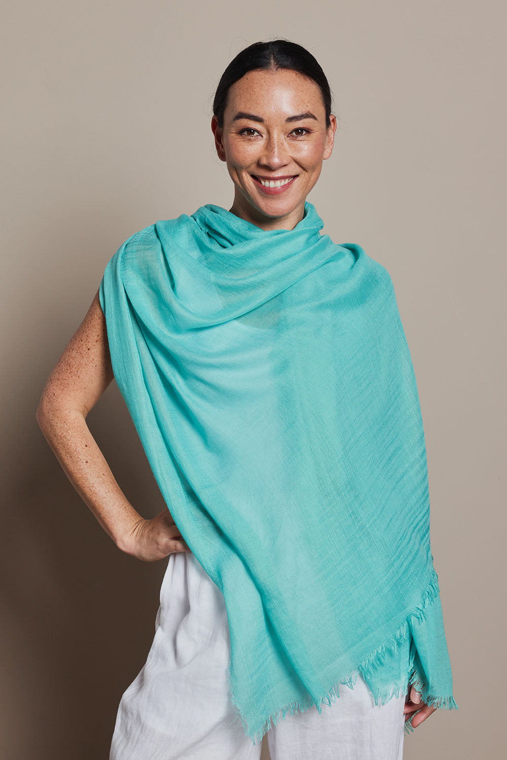 A model wearing the Solid Lightweight Scarf in colour Seafoam (Green), from the front, showing the whole outfit