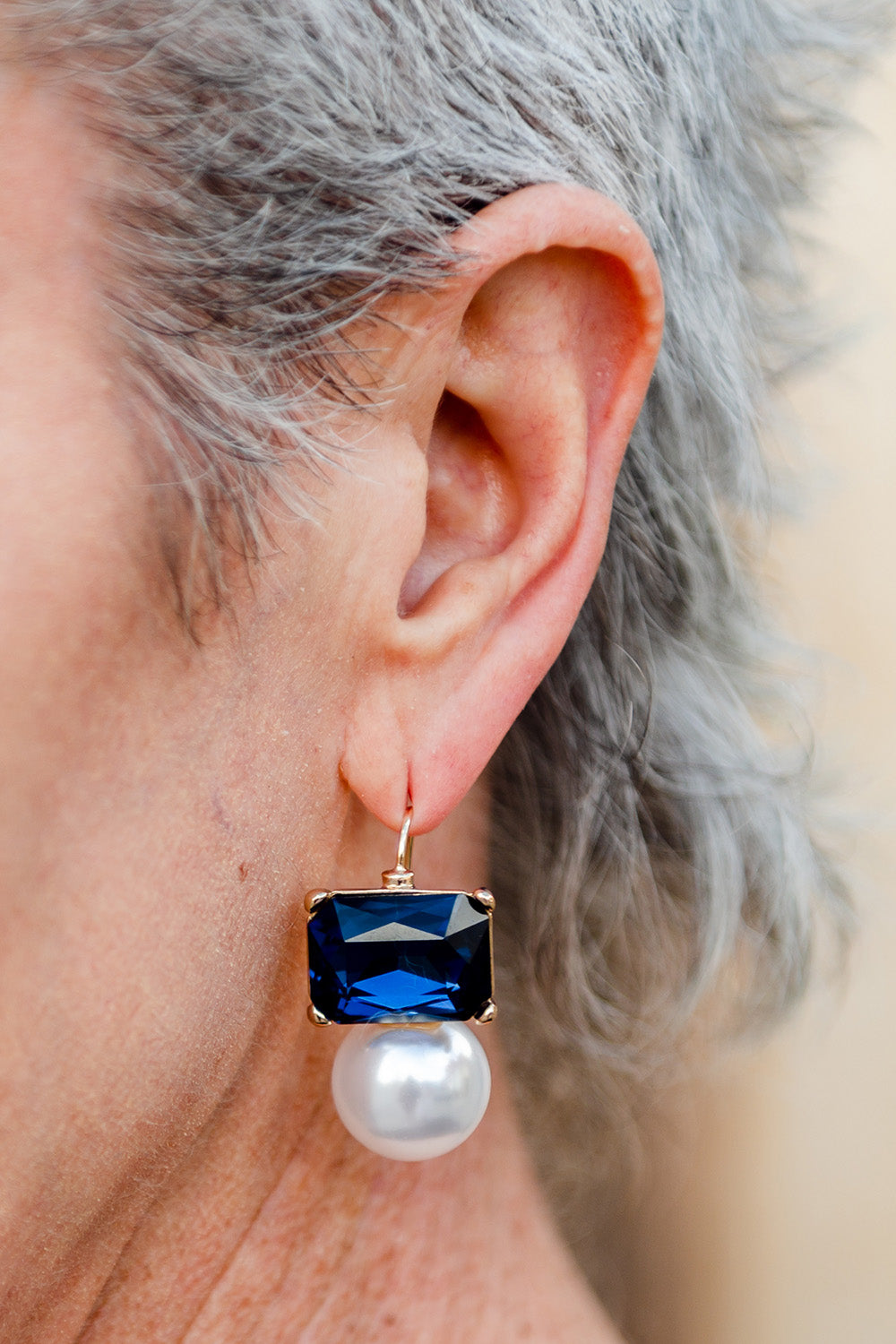 A model wearing the Medium Bling Earrings in colour Navypearl (Blue), from the front, cropped image