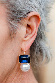 A model wearing the Medium Bling Earrings in colour Navypearl (Blue), from the front, cropped image
