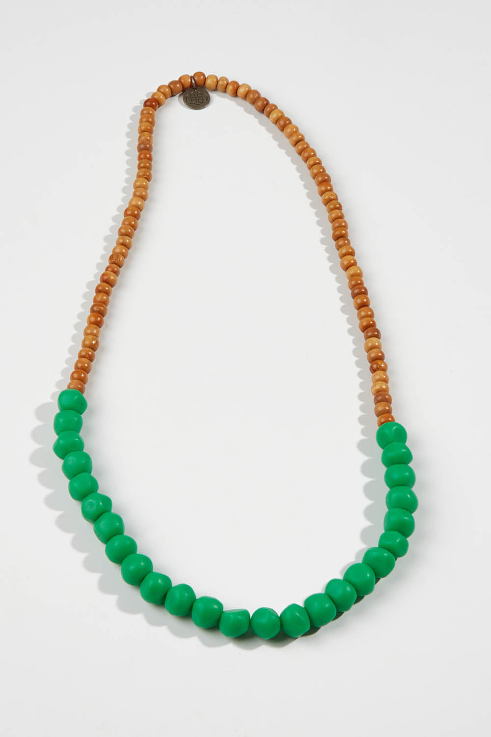 A model wearing size OneSize of the Mini Wood & Rock Necklace in colour Emerald (Green), from the front, showing the whole outfit