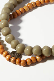 A model wearing size OneSize of the Mini Wood & Rock Necklace in colour Moss (Green), from the front, showing the whole outfit