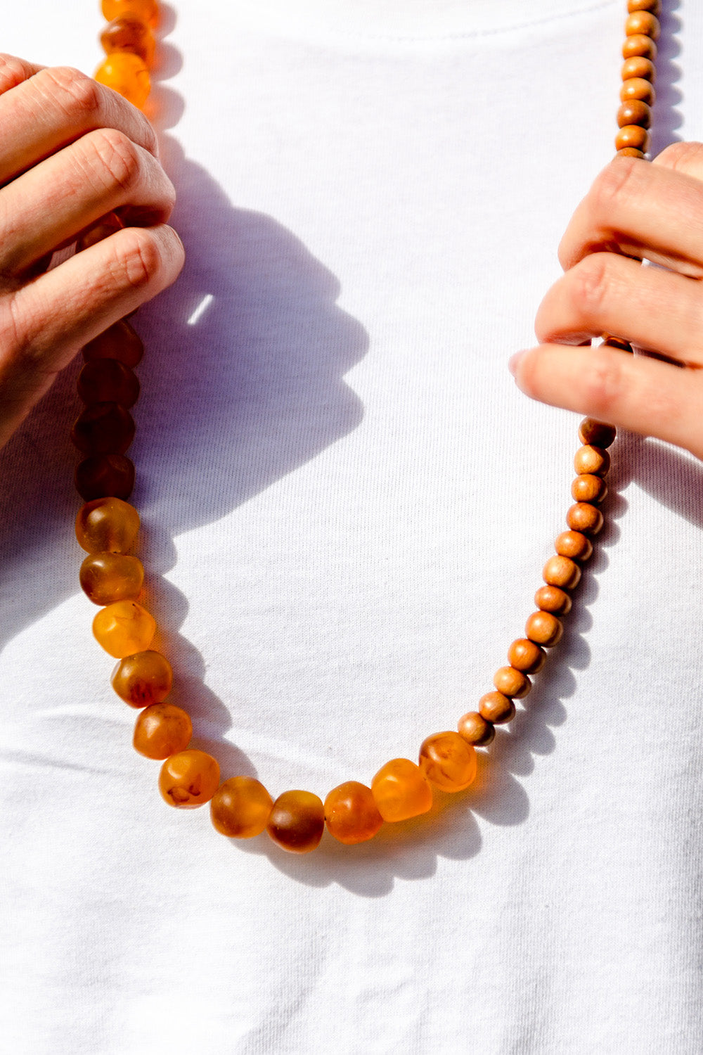 A model wearing the Mini Wood & Rock Necklace in colour Tortoise, from the front, cropped image