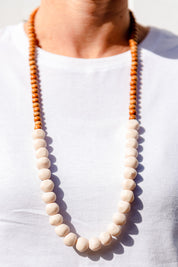 A model wearing the Mini Wood & Rock Necklace in colour White (White), from the front, cropped image