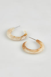 A model wearing the Point Finish Resin Hoop Earring in colour Horn, from the front, showing the whole outfit