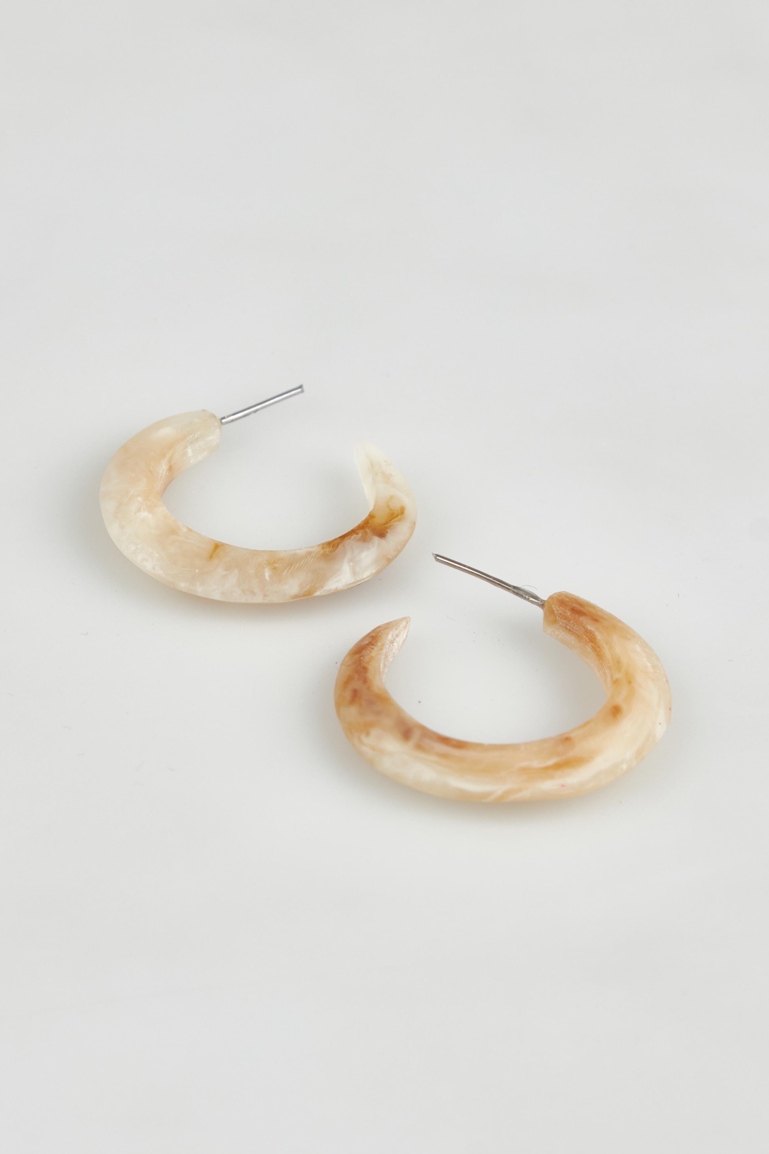 A model wearing the Point Finish Resin Hoop Earring in colour Horn, from the front, showing the whole outfit