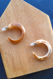 A model wearing the Point Finish Resin Hoop Earring in colour Horn, from the front, showing the whole outfit