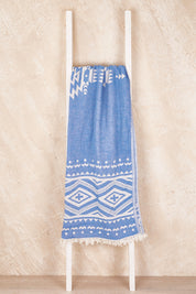 A model wearing the Hammamas Aztec Cotton Towel in colour AztecBlue (Blue), from the front, showing the whole outfit