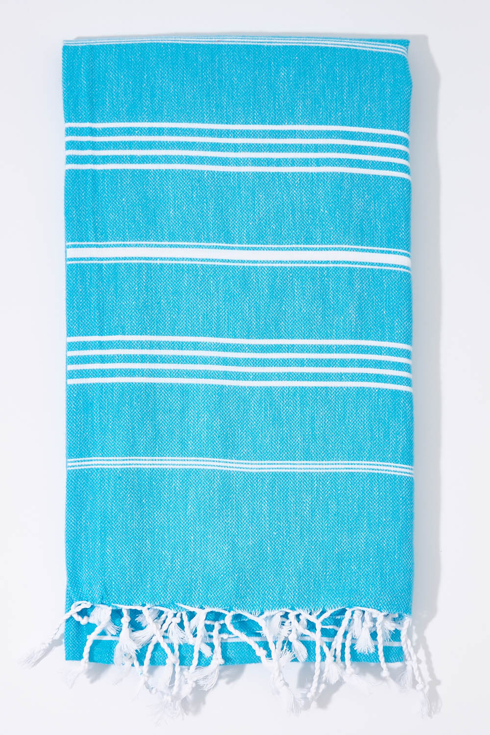 A model wearing the Hammamas Original Cotton Towel in colour Aqua (Blue), from the front, showing the whole outfit