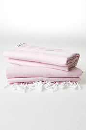 A model wearing the Hammamas Original Cotton Towel in colour Rose (Pink), from the front, showing the whole outfit