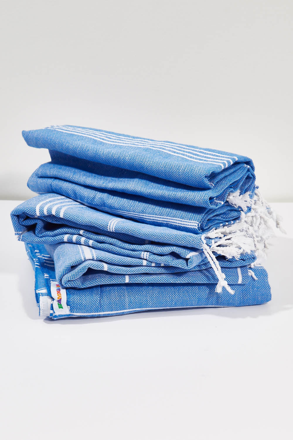 A model wearing the Hammamas Original Cotton Towel in colour Azure (Blue), from the front, showing the whole outfit