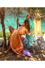 A model wearing the Hammamas Original Cotton Towel in colour Orange