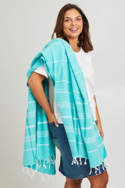Model Monique wearing the Hammamas Original Cotton Towel in colour Spearmint (Green), from the front, cropped image