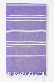 A model wearing the Hammamas Original Cotton Towel in colour Iris (Purple), from the front, showing the whole outfit