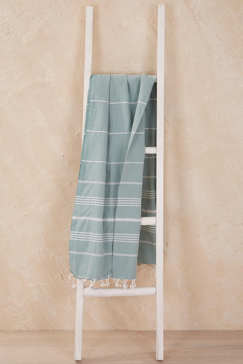 A model wearing the Hammamas Original Cotton Towel in colour Sage (Green), from the front, showing the whole outfit