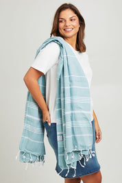 Model Monique wearing the Hammamas Original Cotton Towel in colour Sage (Green), from the front, cropped image
