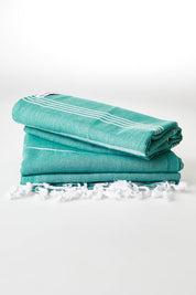 A model wearing size OneSize of the Hammamas Original Towel in colour Emerald (Green), from the front, showing the whole outfit