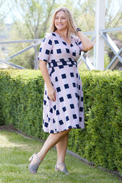 Model Ljubenka wearing size 18 of the Faux Jersey Wrap in colour Checkers (White), from the front, showing the whole outfit