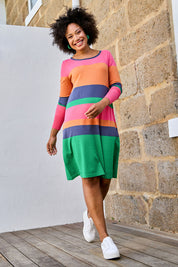 Model Olivia wearing size S of the Knit Stripe Dress in colour Multihues (Pink), from the front, showing the whole outfit