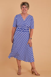 Model Lorraine wearing size 8 of the Printed Short Sleeve Faux Wrap Dress in colour Waves (Blue), from the front, showing the whole outfit