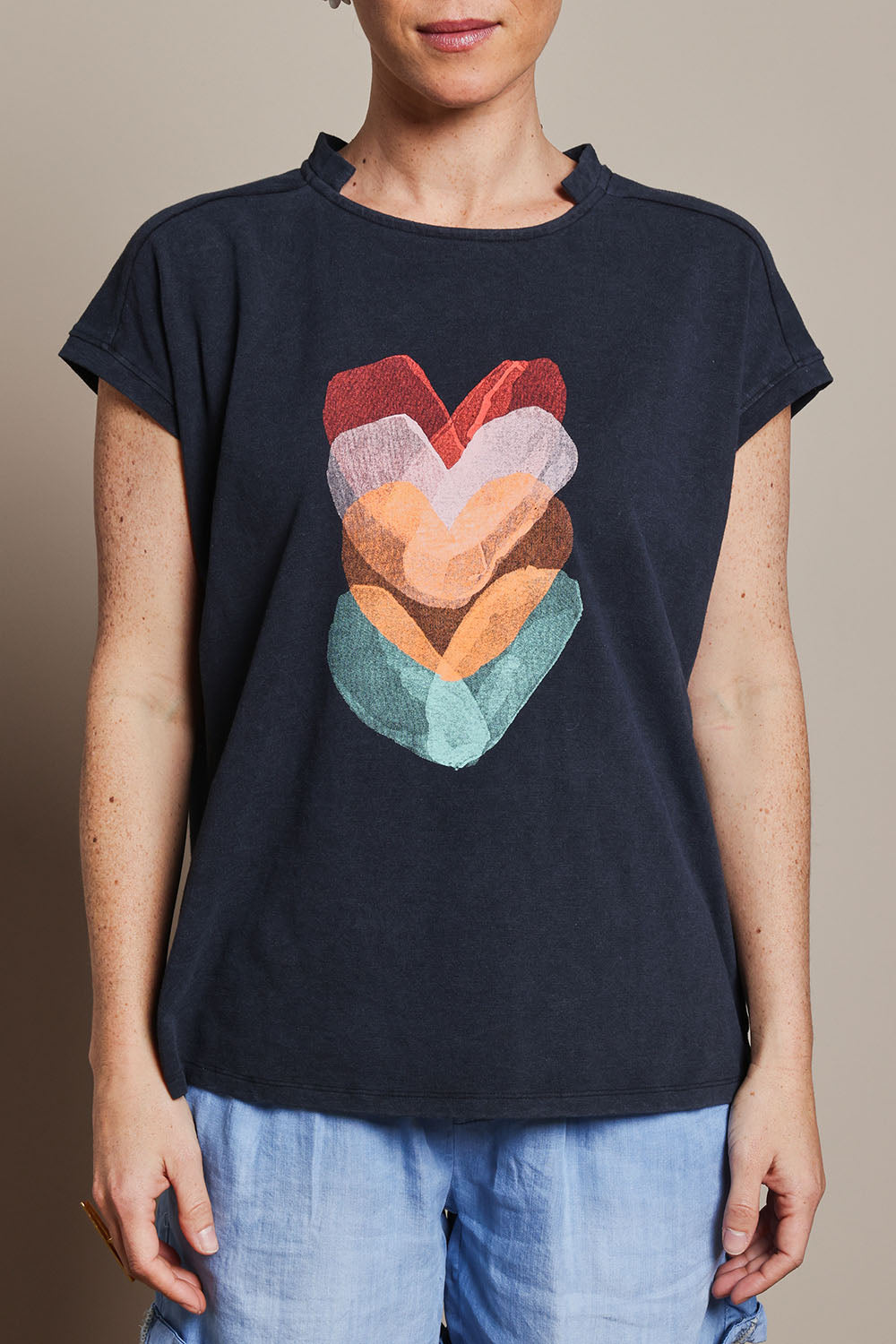 Model Katie wearing size 10 of the Heart Logo Tee in colour Orgheart, from the front, cropped image