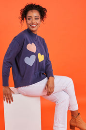 Model Noli wearing size L of the Heart Sweater in colour Hearts (Blue), from the front, showing the whole outfit