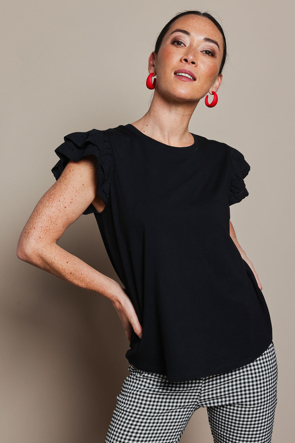 Model Katie wearing size 10 of the Ruffle Sleeve Top in colour Black (Black), from the front, cropped image