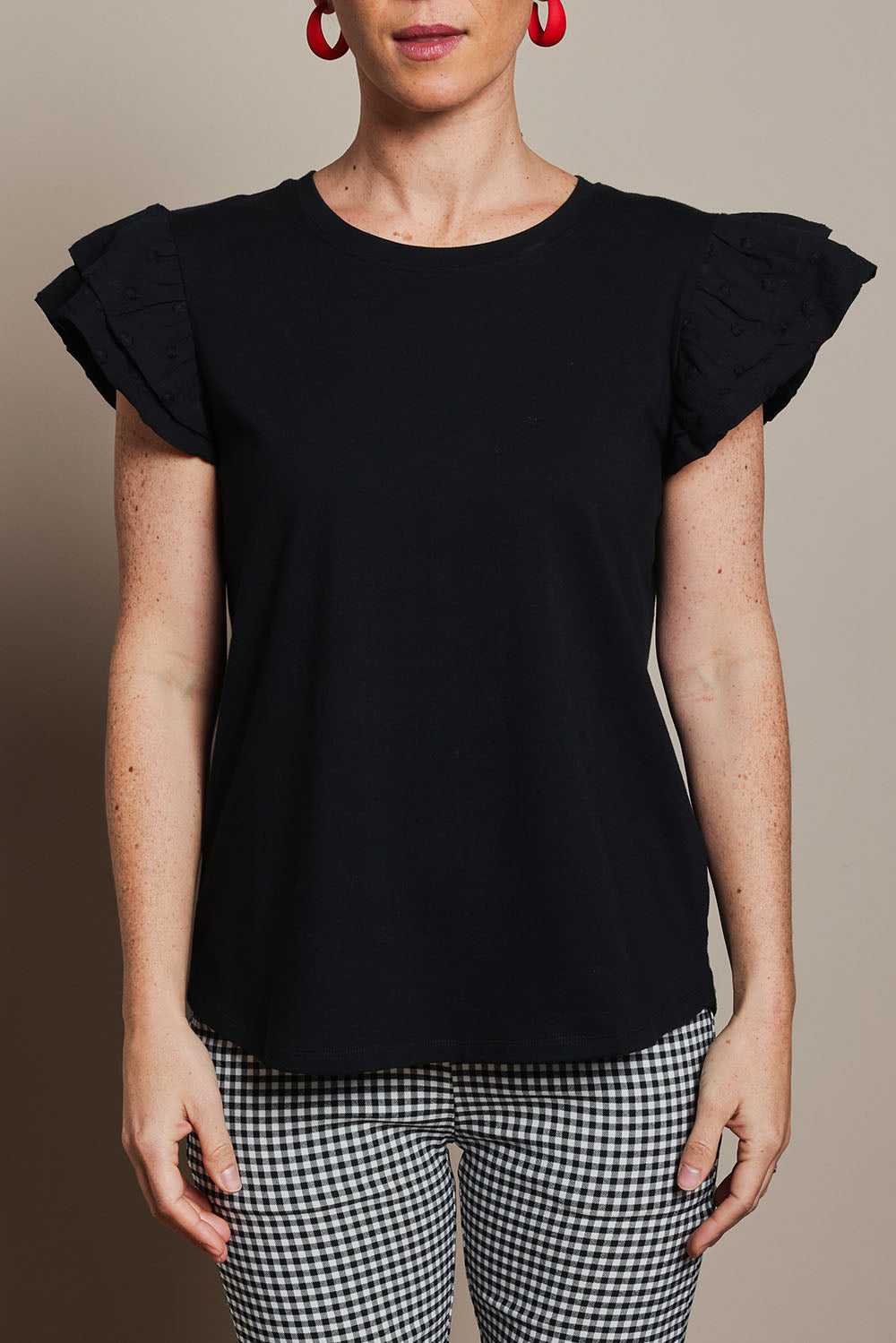 Model Katie wearing size 10 of the Ruffle Sleeve Top in colour Black (Black), from the front, cropped image