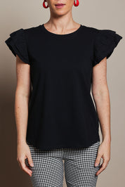 Model Katie wearing size 10 of the Ruffle Sleeve Top in colour Black (Black), from the front, cropped image