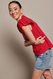 Model Katie wearing size 10 of the Ruffle Sleeve Top in colour Lollipop (Red), from the front, cropped image