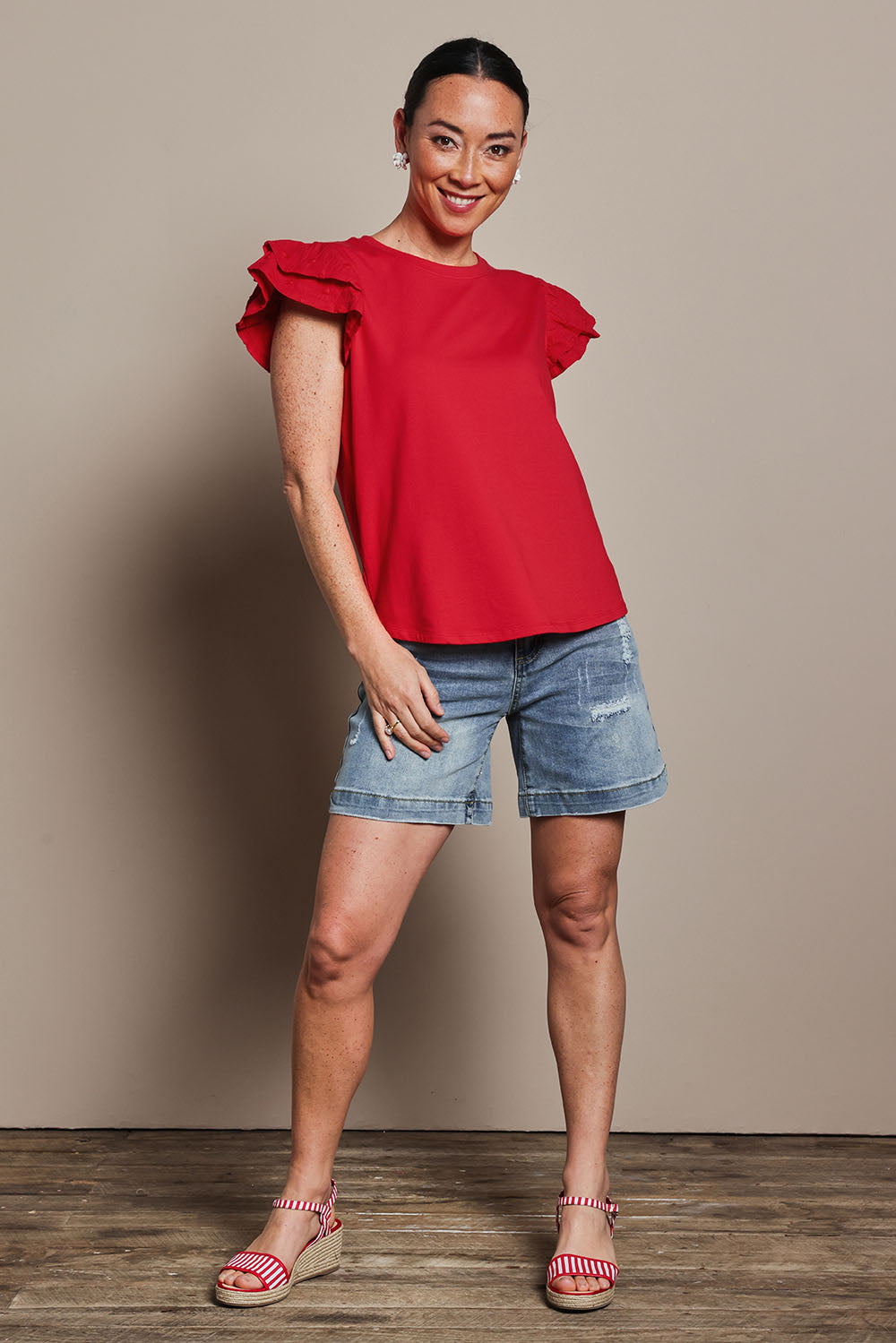 Model Katie wearing size 10 of the Ruffle Sleeve Top in colour Lollipop (Red), from the front, showing the whole outfit