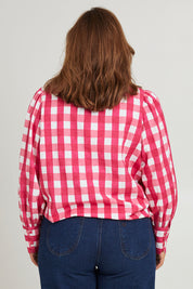 Model Monique wearing size 14 of the Printed Tie Neck Blouse in colour Berrycheck (Pink), from the back