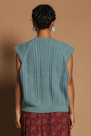 Model Katie wearing the Cable Vest in colour Bluehaze (Blue), from the back