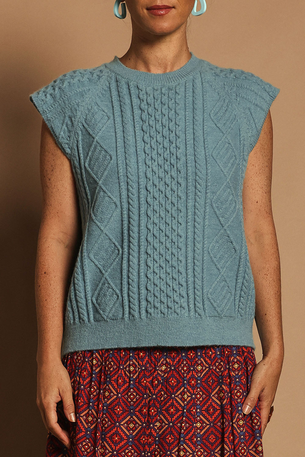 Model Katie wearing the Cable Vest in colour Bluehaze (Blue), from the front, cropped image