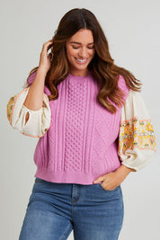 Model Laura wearing the Cable Vest in colour Cable (Pink), from the front, cropped image