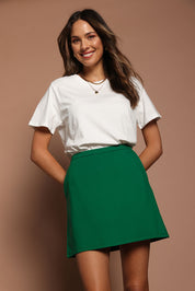 Model Madeline wearing size 10 of the Ponte Mini Skirt in colour Green (Green), from the front, cropped image