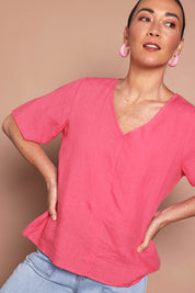 Model Katie wearing size 10 of the Linen Elastane V Neck Blouse in colour Melon (Pink), from the front, cropped image