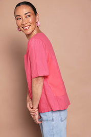 Model Katie wearing size 10 of the Linen Elastane V Neck Blouse in colour Melon (Pink), from the front, showing the whole outfit