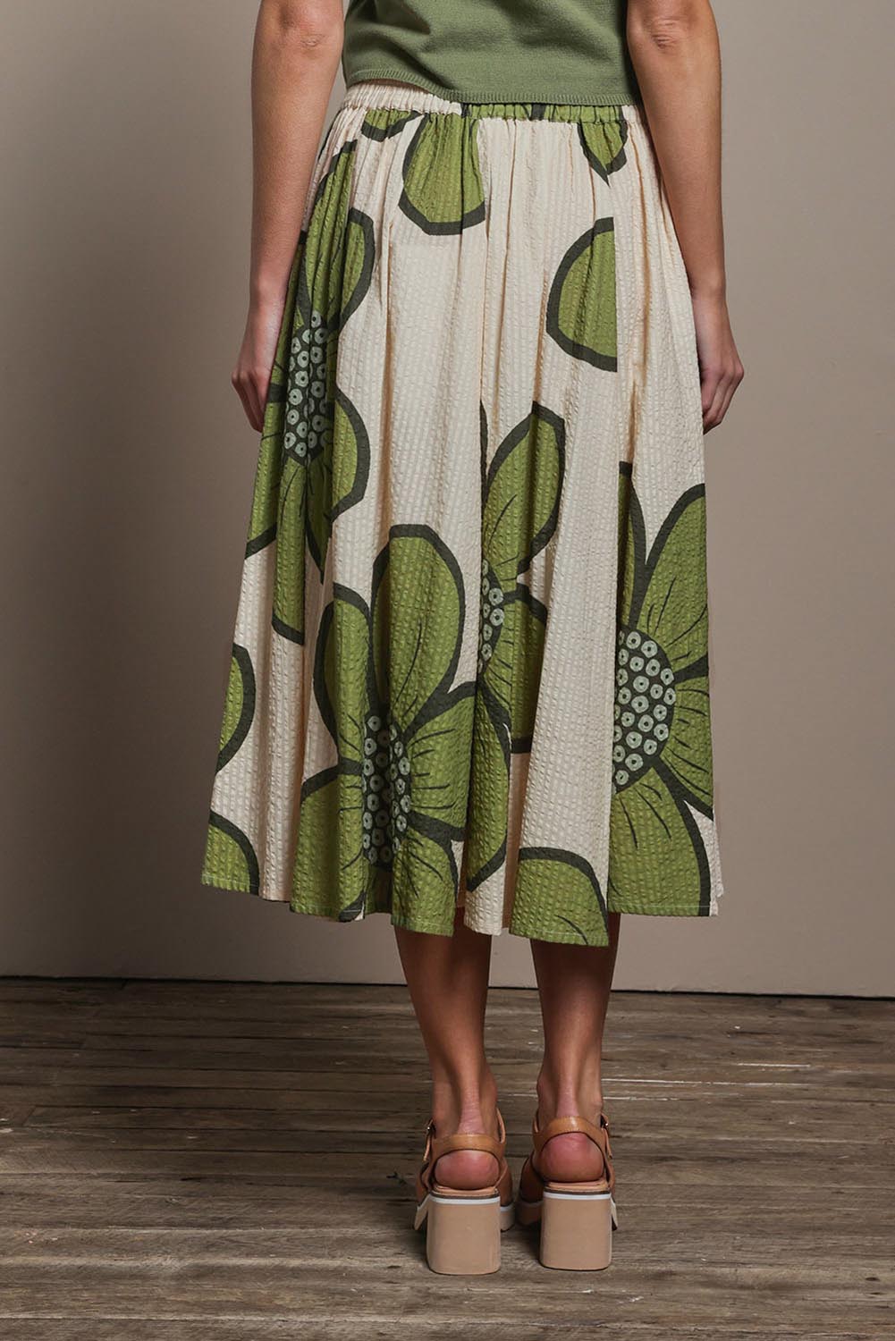 Model Madeline wearing size 10 of the Cotton Flower Skirt in colour Boldflower (Green), from the back