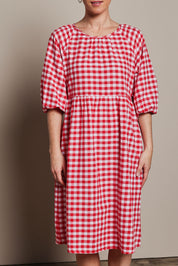 Model Katie wearing size 10 of the Cotton Empire Waist Dress in colour Ginghamred (Red), from the front, cropped image