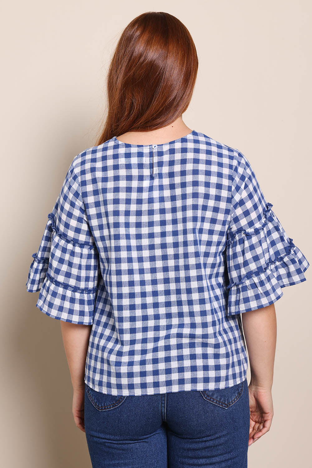 Model Georgiel wearing size 10 of the Cotton Gingham Frill Blouse – Blue in colour Blue, from the back