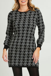 Model Grace wearing size S of the Abigail Sweater Dress in colour Houndstoo (Black), from the front, cropped image