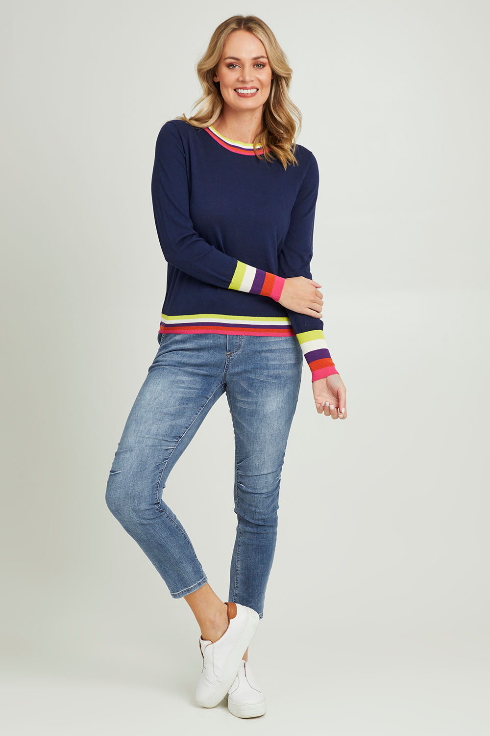 Model Grace wearing size S of the Emma Sweater in colour Rainbowstp (Blue), from the front, showing the whole outfit