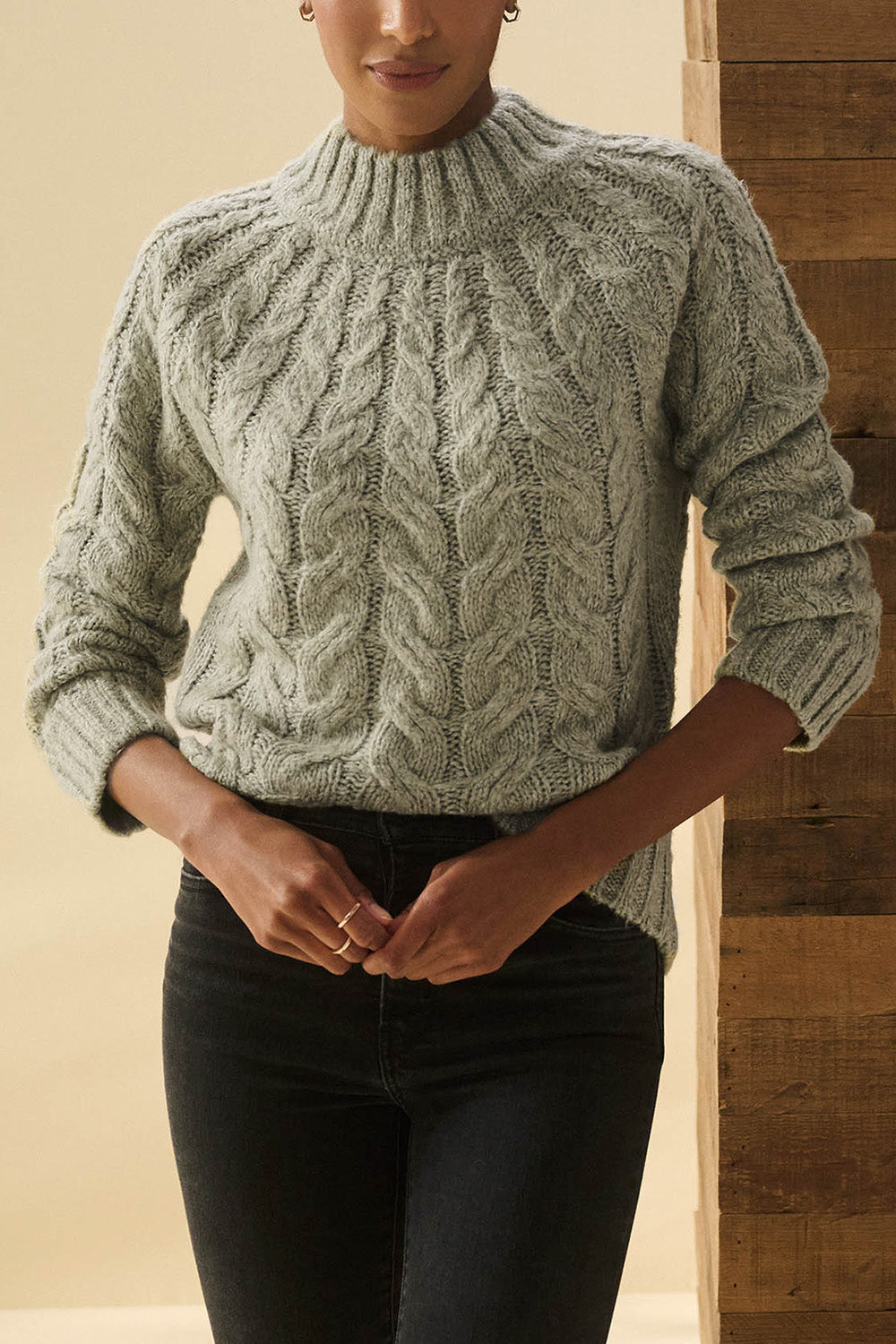 A model wearing the Dylan Cable Knit Sweater in colour Moss (Green), from the front, cropped image