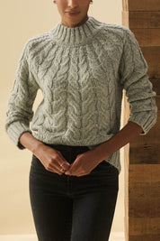 A model wearing the Dylan Cable Knit Sweater in colour Moss (Green), from the front, cropped image