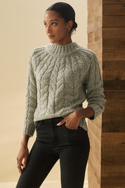 A model wearing the Dylan Cable Knit Sweater in colour Moss (Green), from the front, cropped image