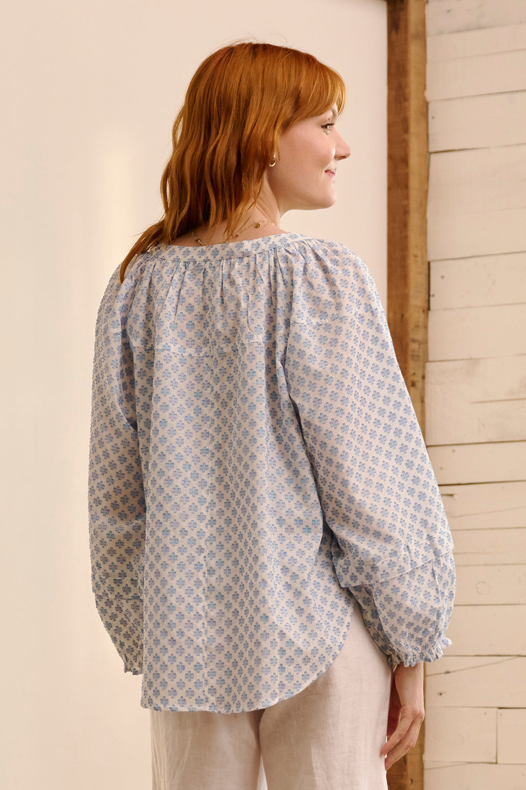 A model wearing the Naomi Cotton Blend Blouse in colour Petal (Blue), from the back