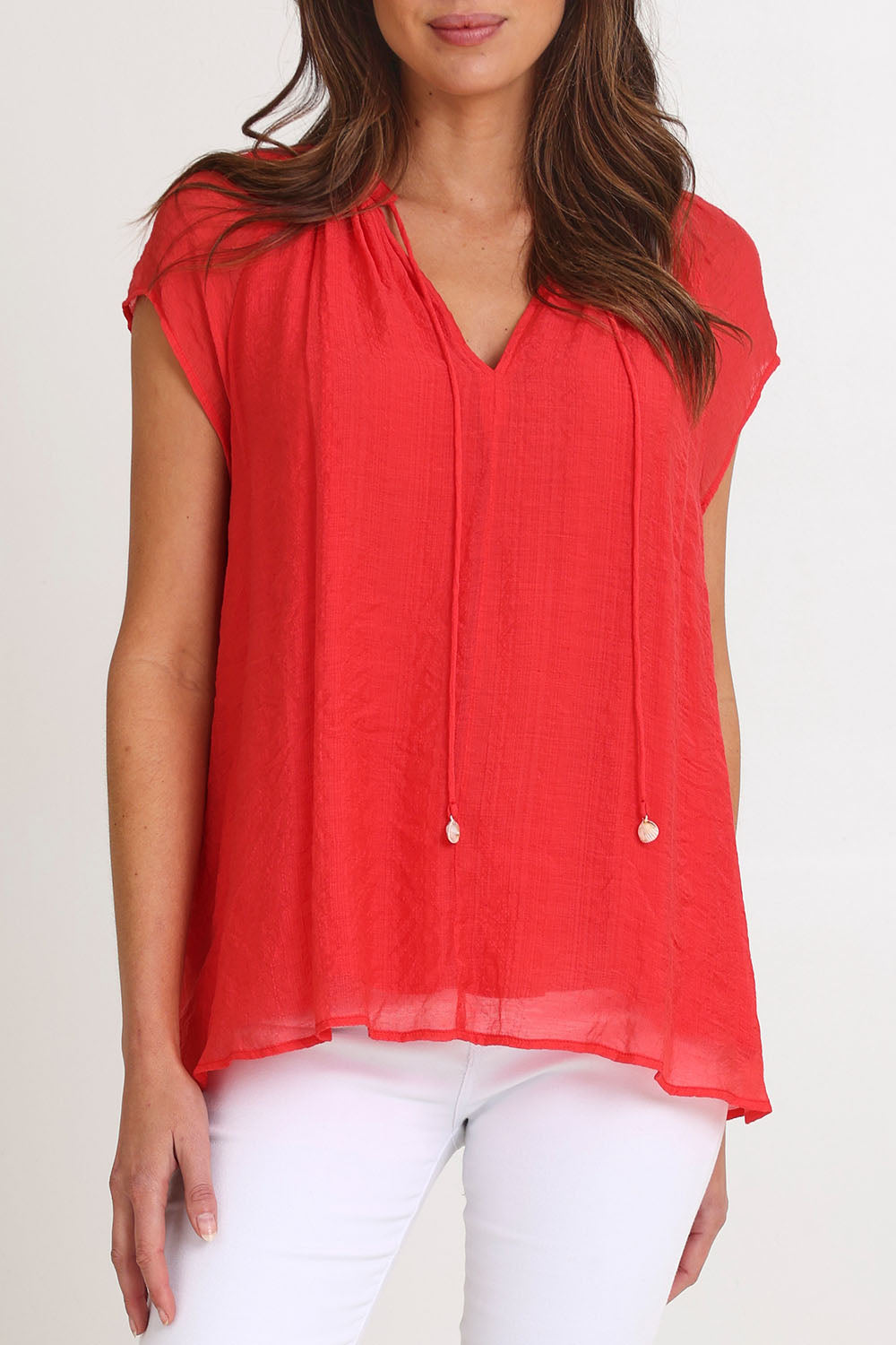 Model Madeline wearing size S of the Baja Top in colour Punch (Red), from the front, cropped image