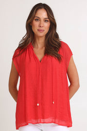 Model Monique wearing size S of the Baja Top in colour Punch (Red), from the front, cropped image